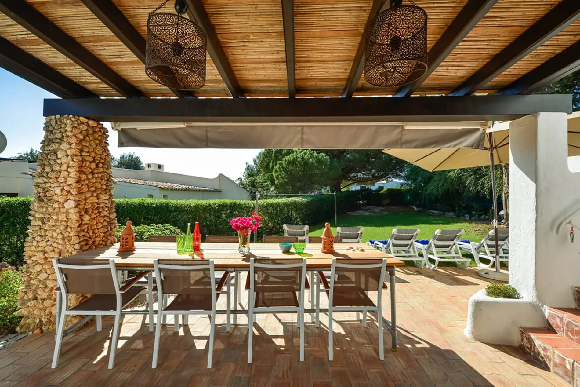 Outdoor patio with dining table, chairs, and garden view.