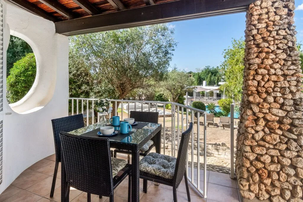 Table on a sunny balcony with a garden view.