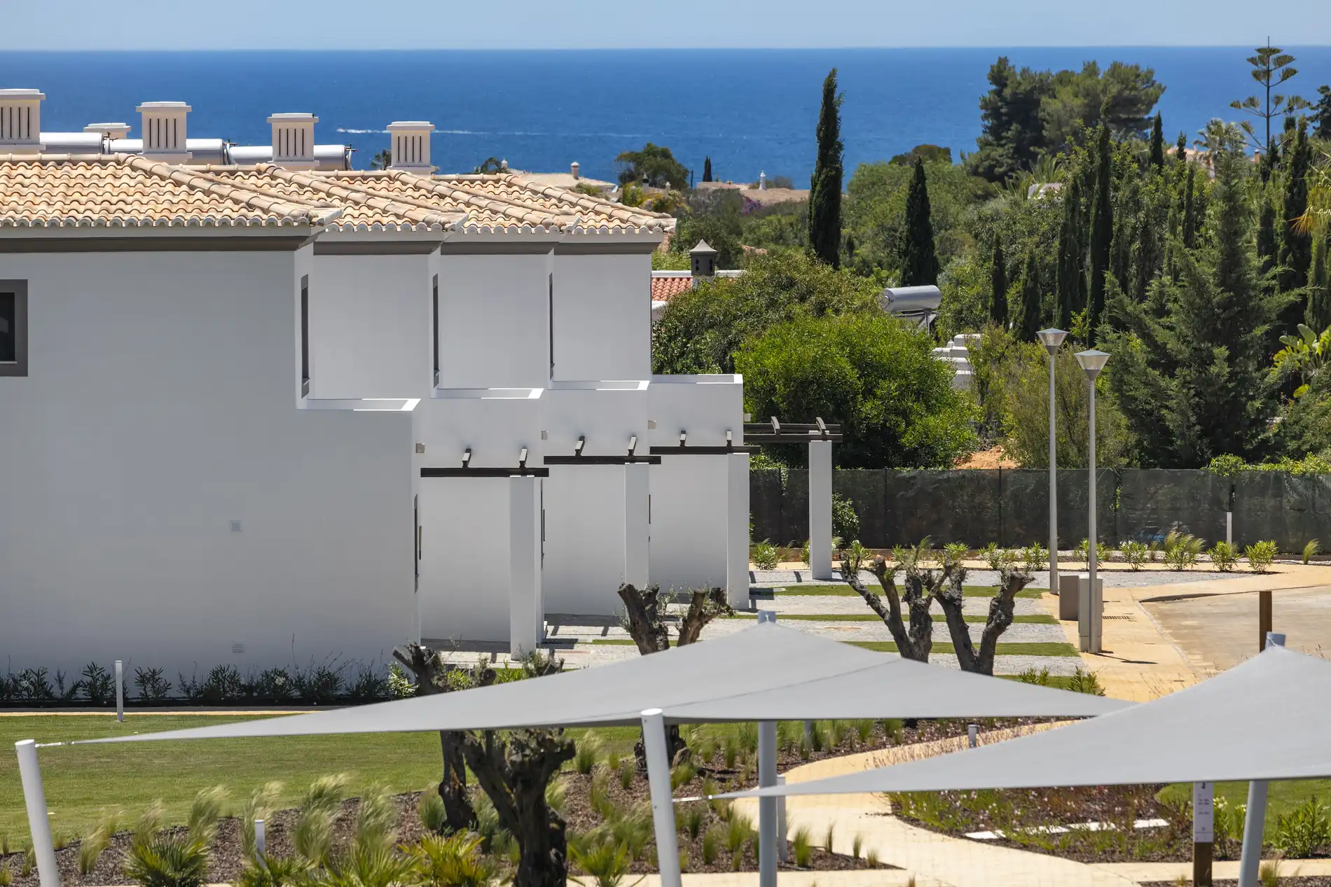 White buildings and trees near the sea with a clear blue sky.