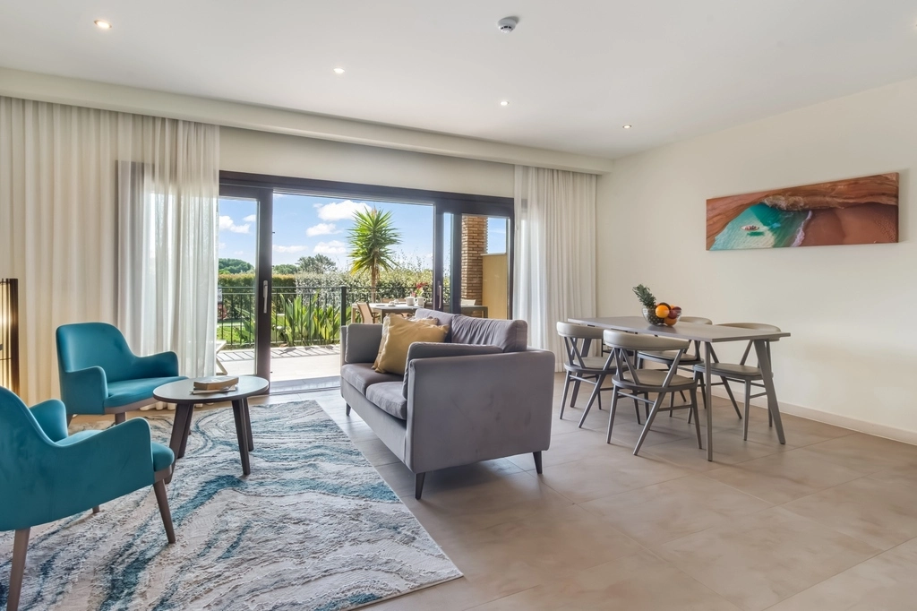 Modern living room with dining area, large window, and blue chairs.