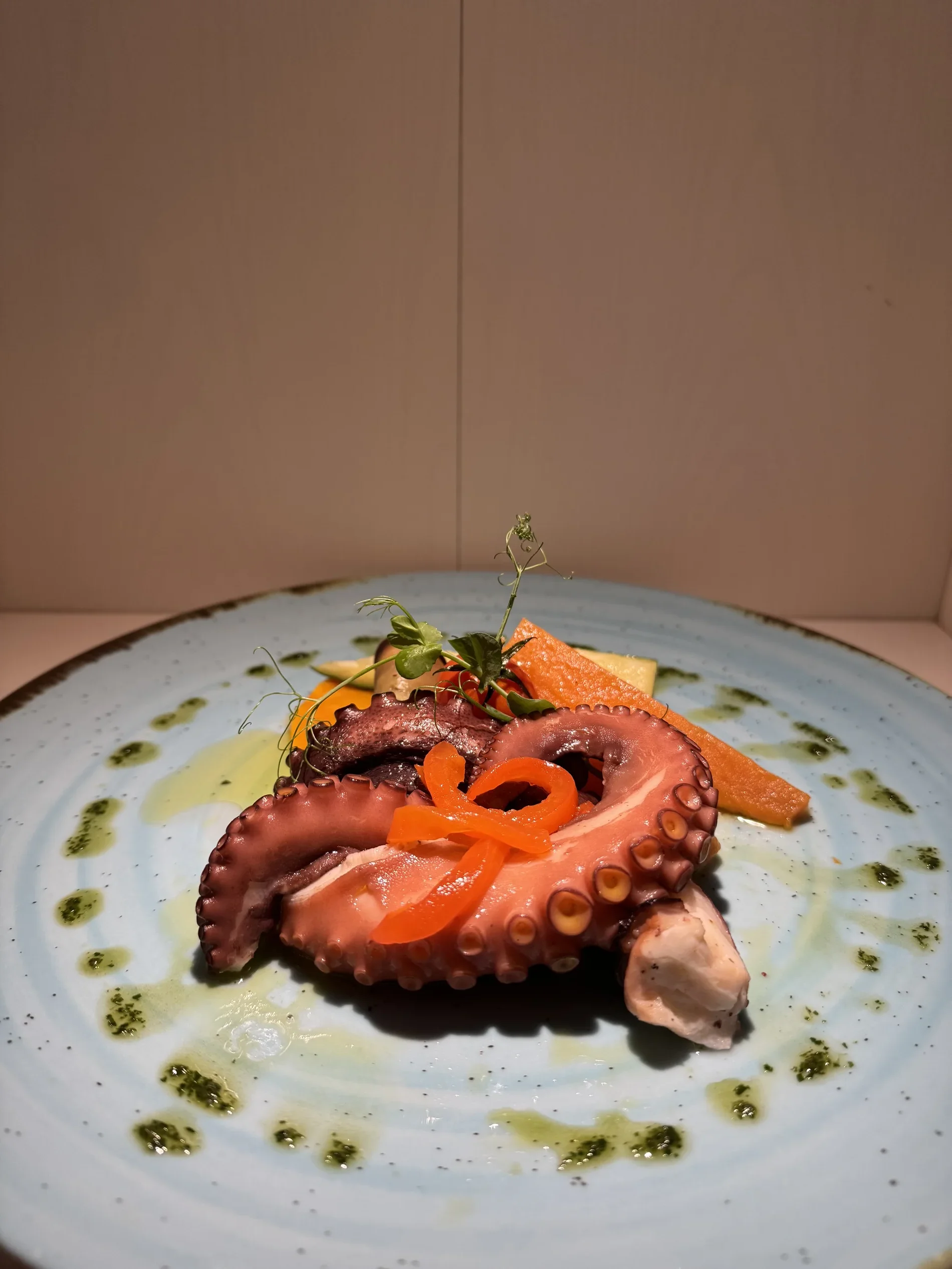Gourmet octopus dish on a blue plate with garnish.
