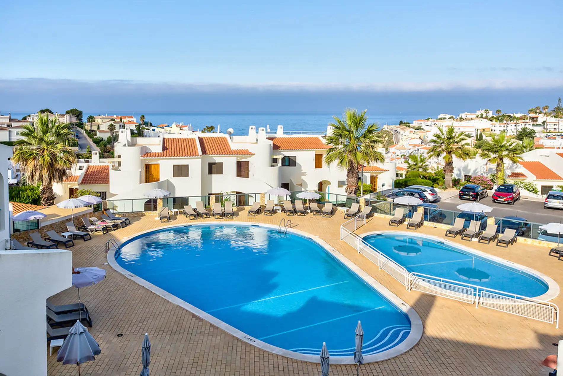 Rooftop pool with loungers and ocean view on a sunny day.
