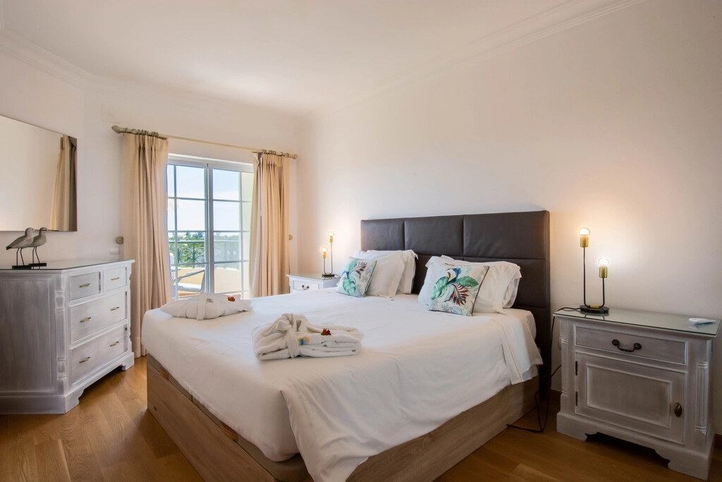 A cozy bedroom with a double bed, two nightstands, and large window.
