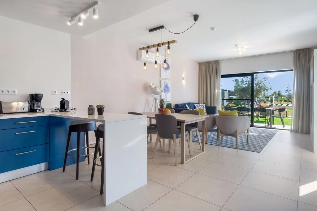 Modern open-plan kitchen and living room with large windows and elegant decor.