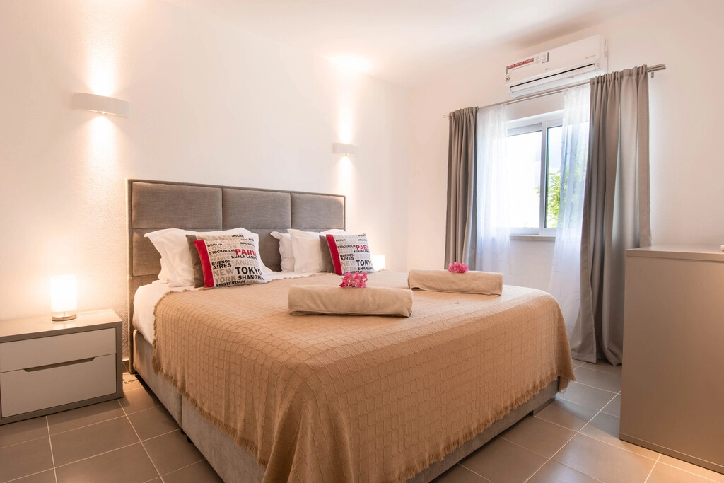 Cozy bedroom with a double bed, neutral tones, and window curtains for natural light.