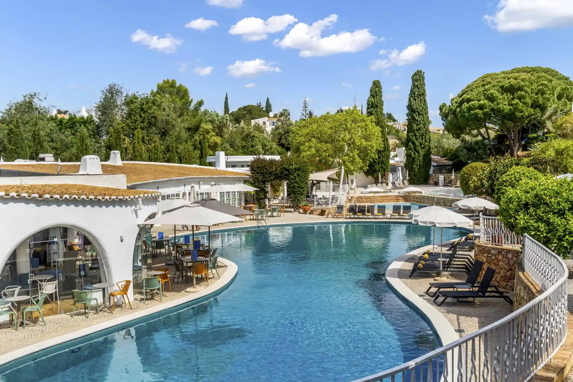 A serene poolside setting with trees and umbrellas.