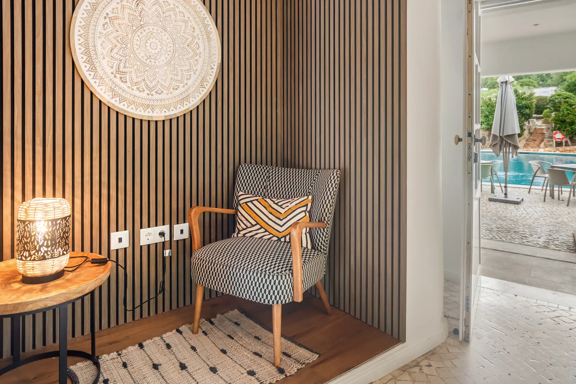Stylish chair and lamp in a cozy corner by a poolside view.
