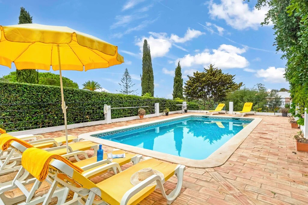 Sunny poolside with yellow loungers and umbrella.