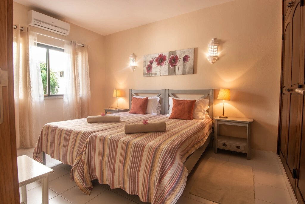 Cozy bedroom with twin beds, striped bedding, and floral wall art.