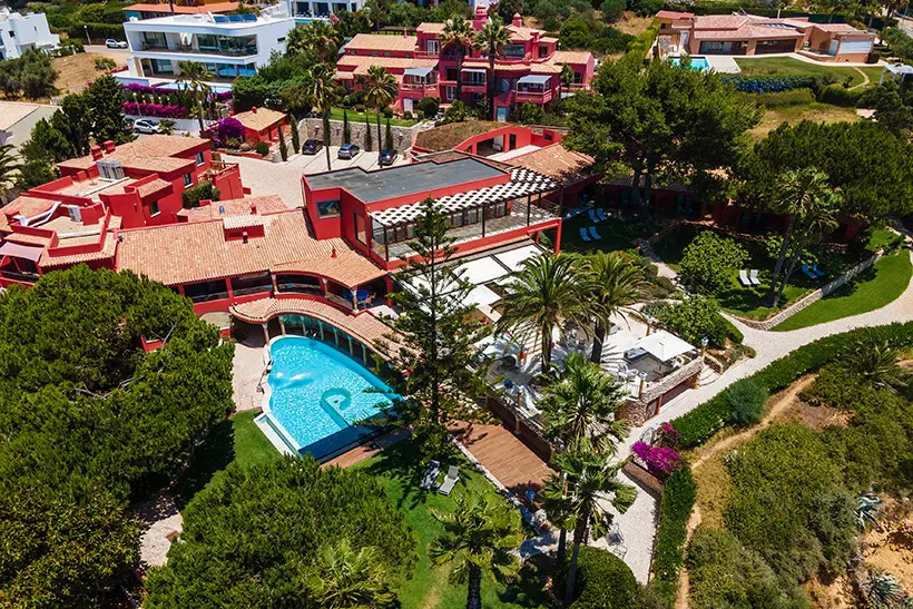 Aerial view of a large villa with a pool surrounded by trees and gardens.