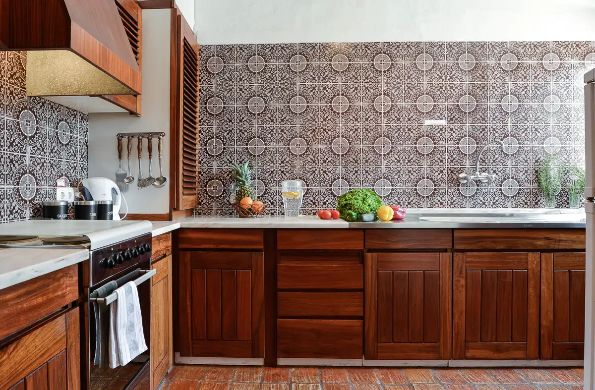 Retro kitchen with brown cabinets, patterned tiles, and fresh vegetables on the counter.