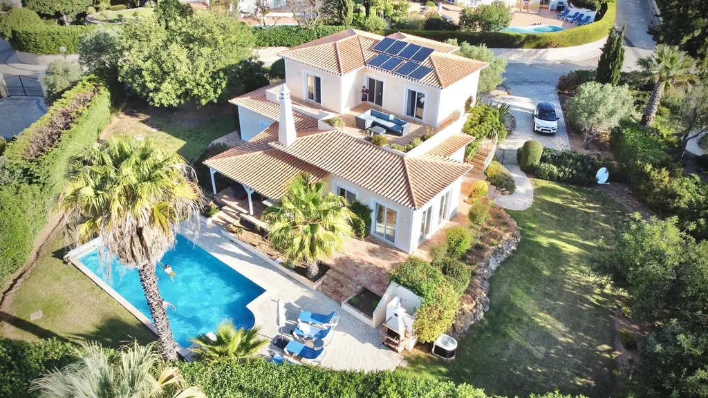 Aerial view of a house with a patio, pool, and garden.