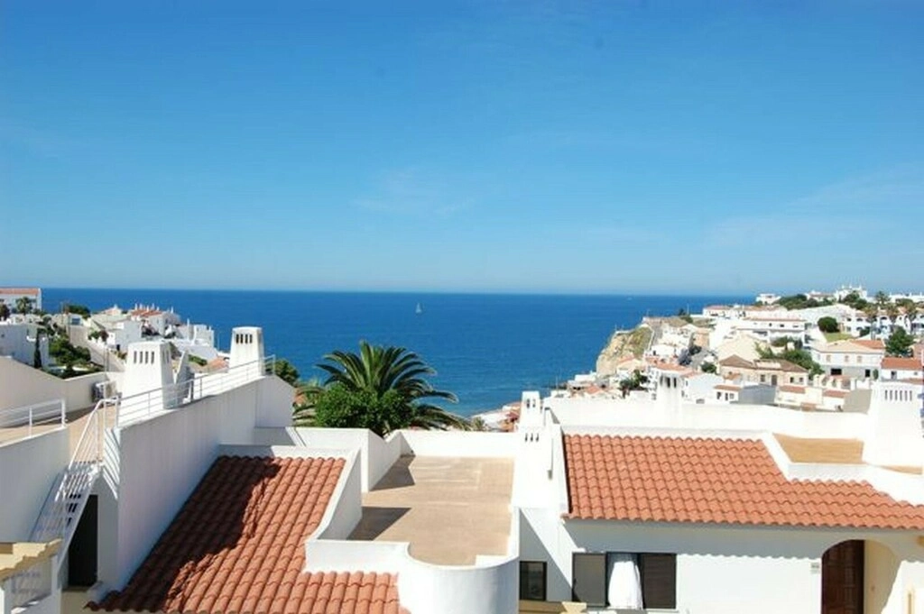 Coastal view with white buildings, sea, and blue sky.
