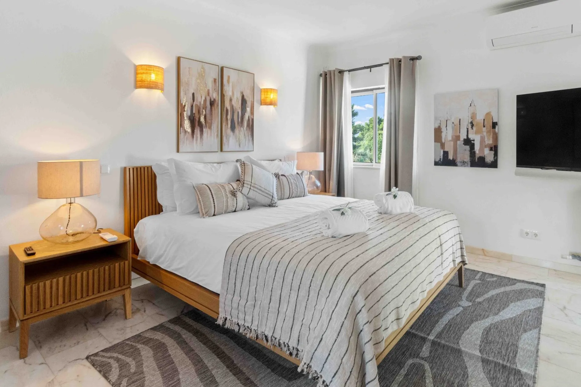 Modern bedroom with striped bedding and abstract art above the bed.