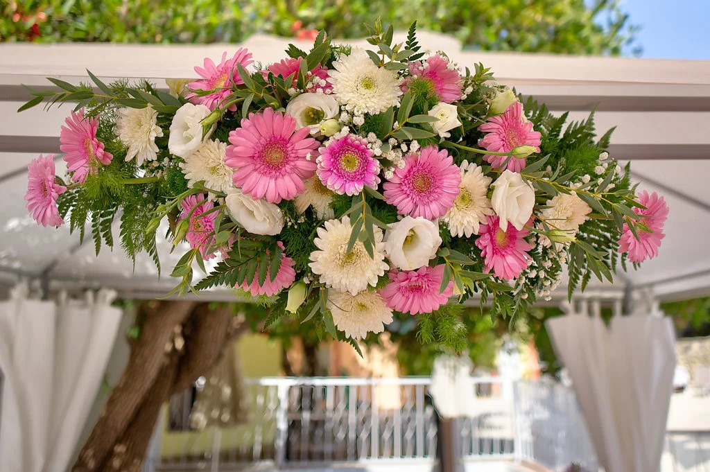 Pink and white flower arrangement with green leaves.