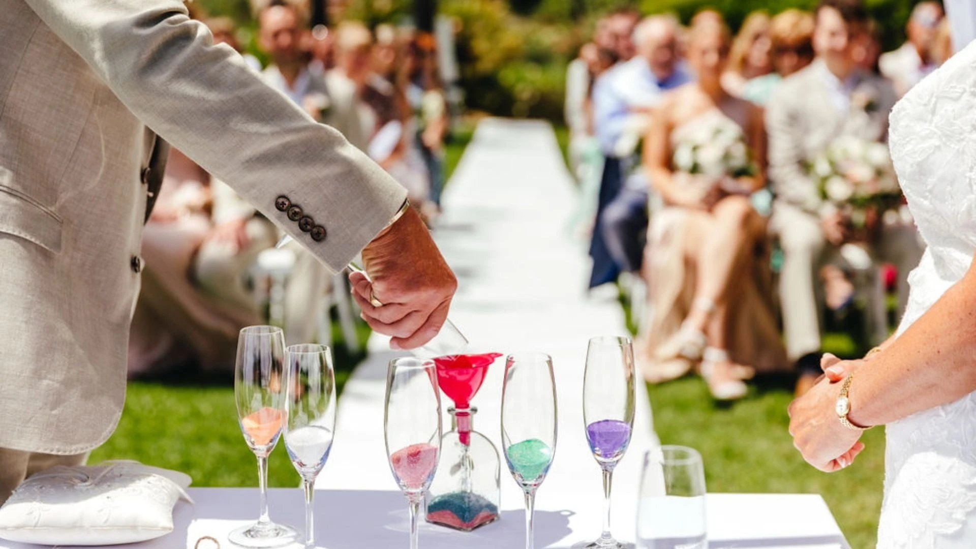 Couple pouring colored sand into a bottle at a wedding ceremony.