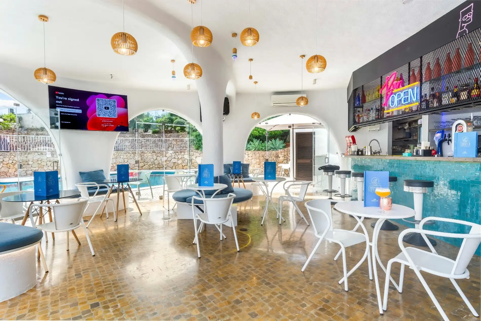 Modern cafe with blue accents, open seating, and a pool view.
