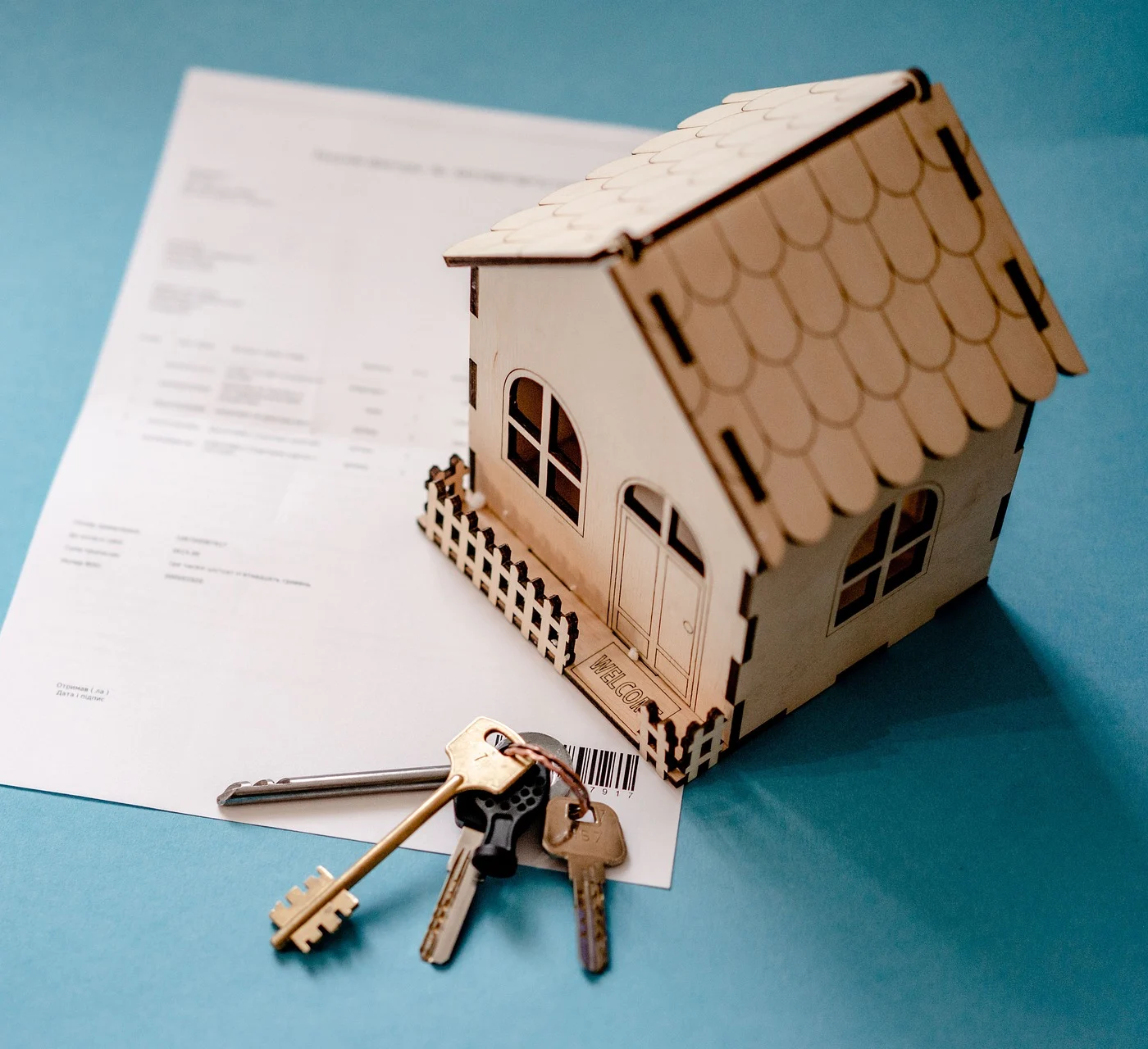 Toy house on paper with keys on a blue background.