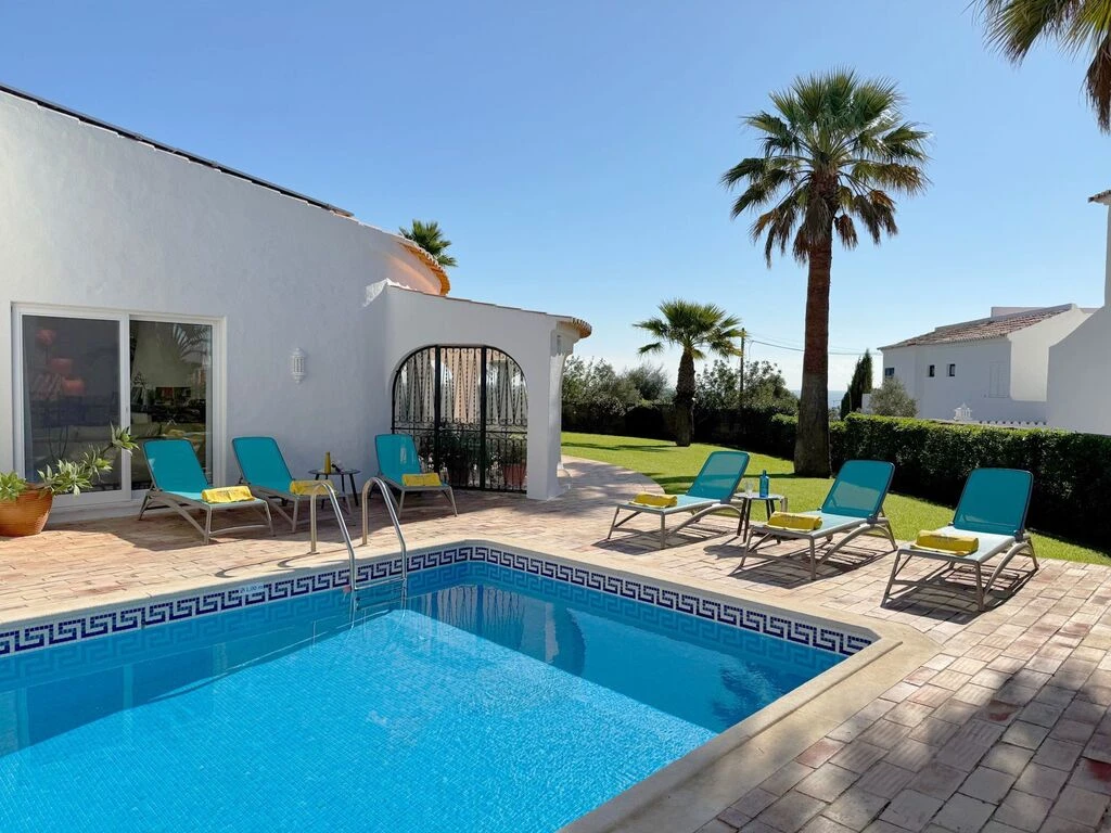 Sunny poolside with lounge chairs and palm trees.