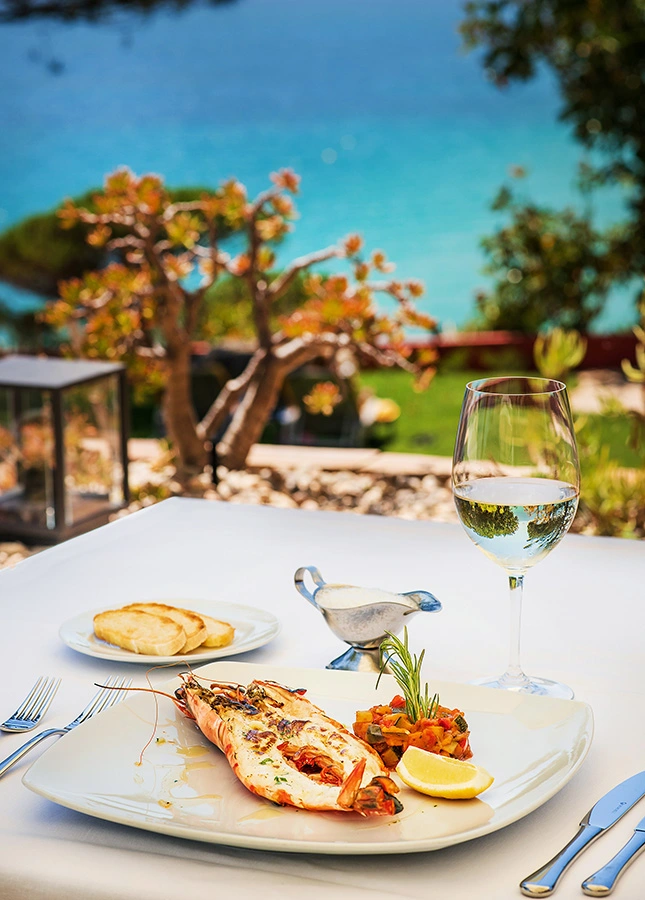 Seafood platter and wine on an outdoor table with an ocean view.