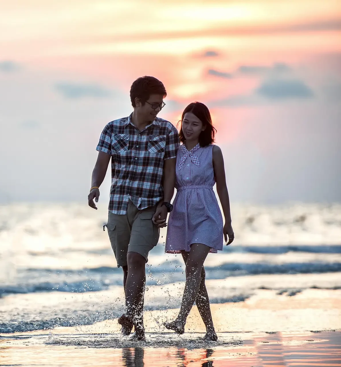 Couple walking on the beach at sunset.