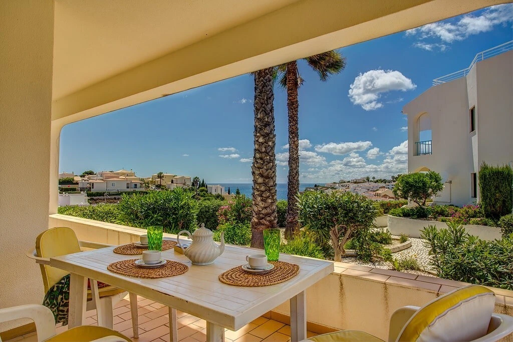 Sea view patio with table set for four under a sunny blue sky.