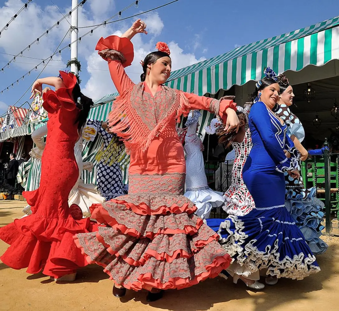Mujeres bailando flamenco con coloridos trajes tradicionales.