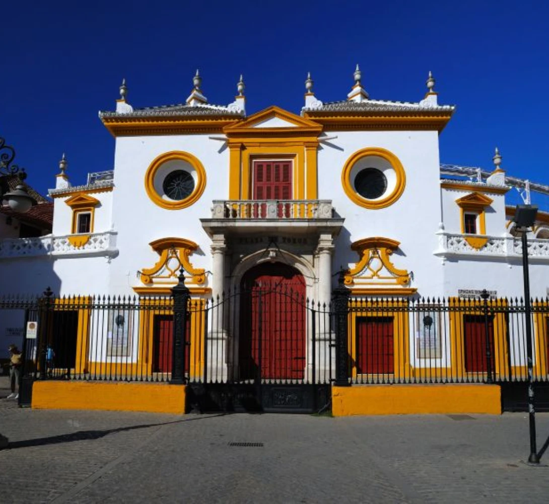 Edificio blanco con detalles amarillos, puertas rojas, cielo azul.