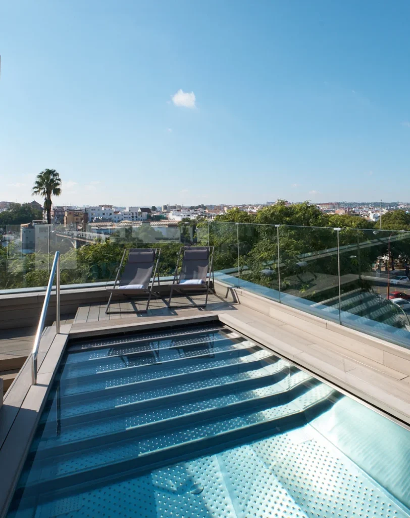 Piscina en la azotea con tumbonas y vista panor&aacute;mica de la ciudad.