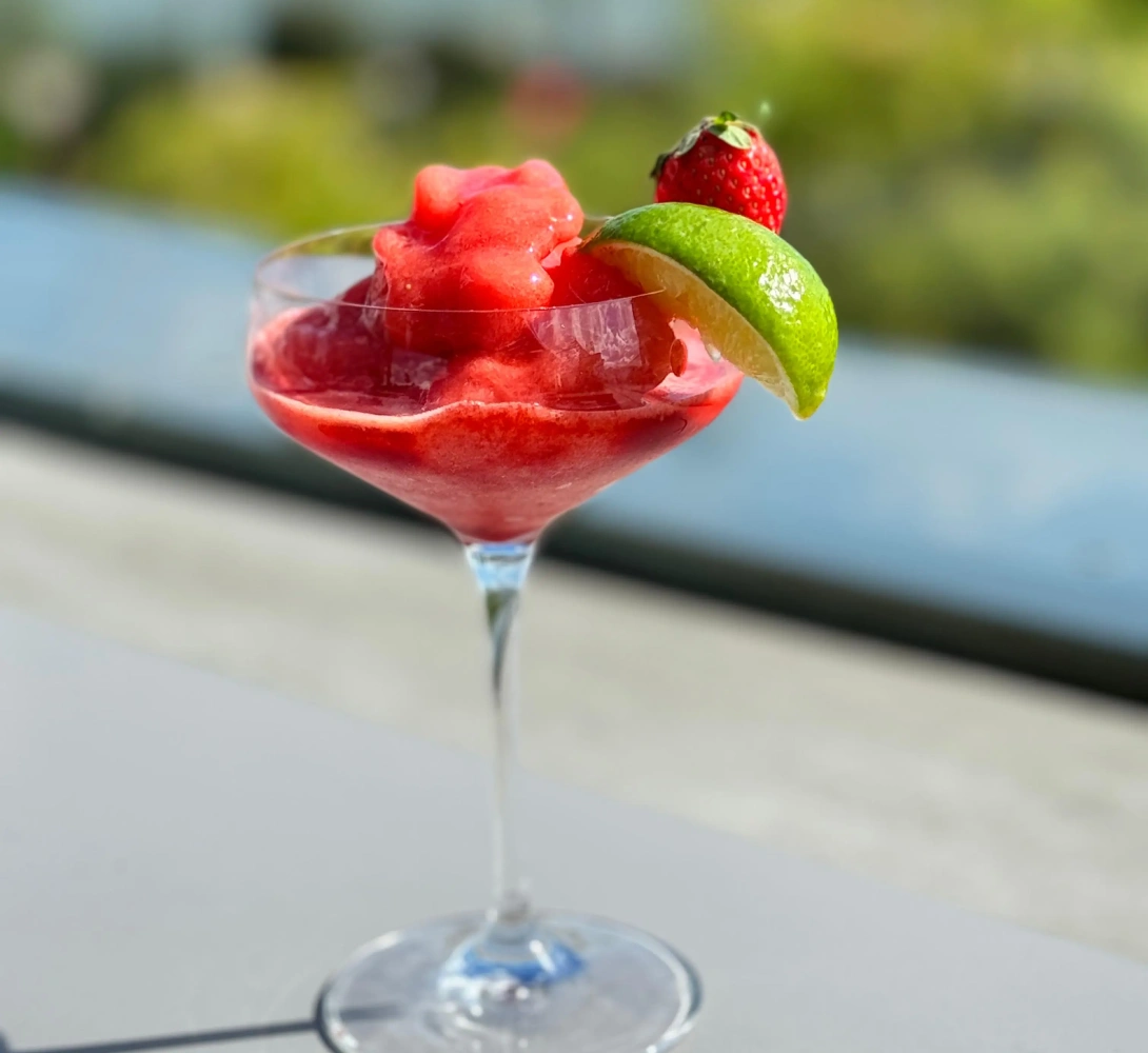 Copa de c&oacute;ctel de fresa con hielo, decorada con fresa y lima.