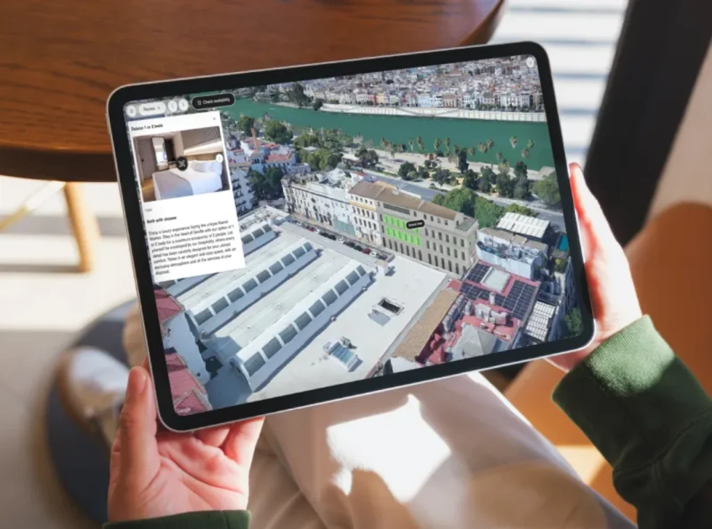 Persona sosteniendo tablet con imagen a&eacute;rea de edificios y un r&iacute;o.
