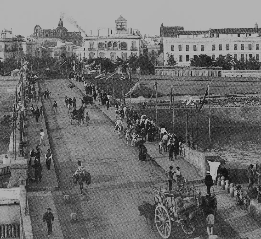 Antiguo puente concurrido con carros tirados por bueyes y personas caminando.