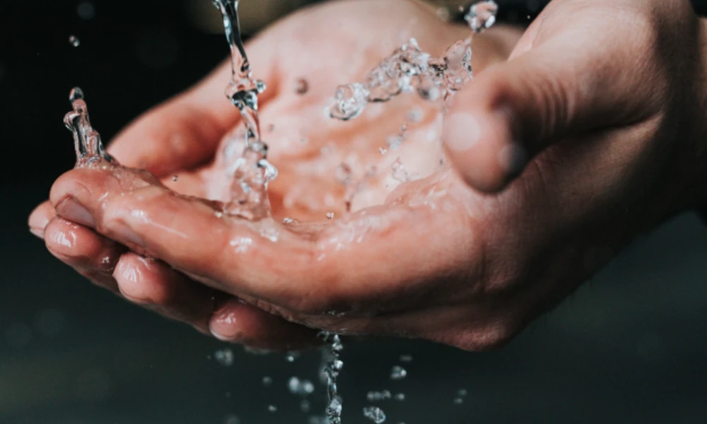 Manos sosteniendo agua corriente.