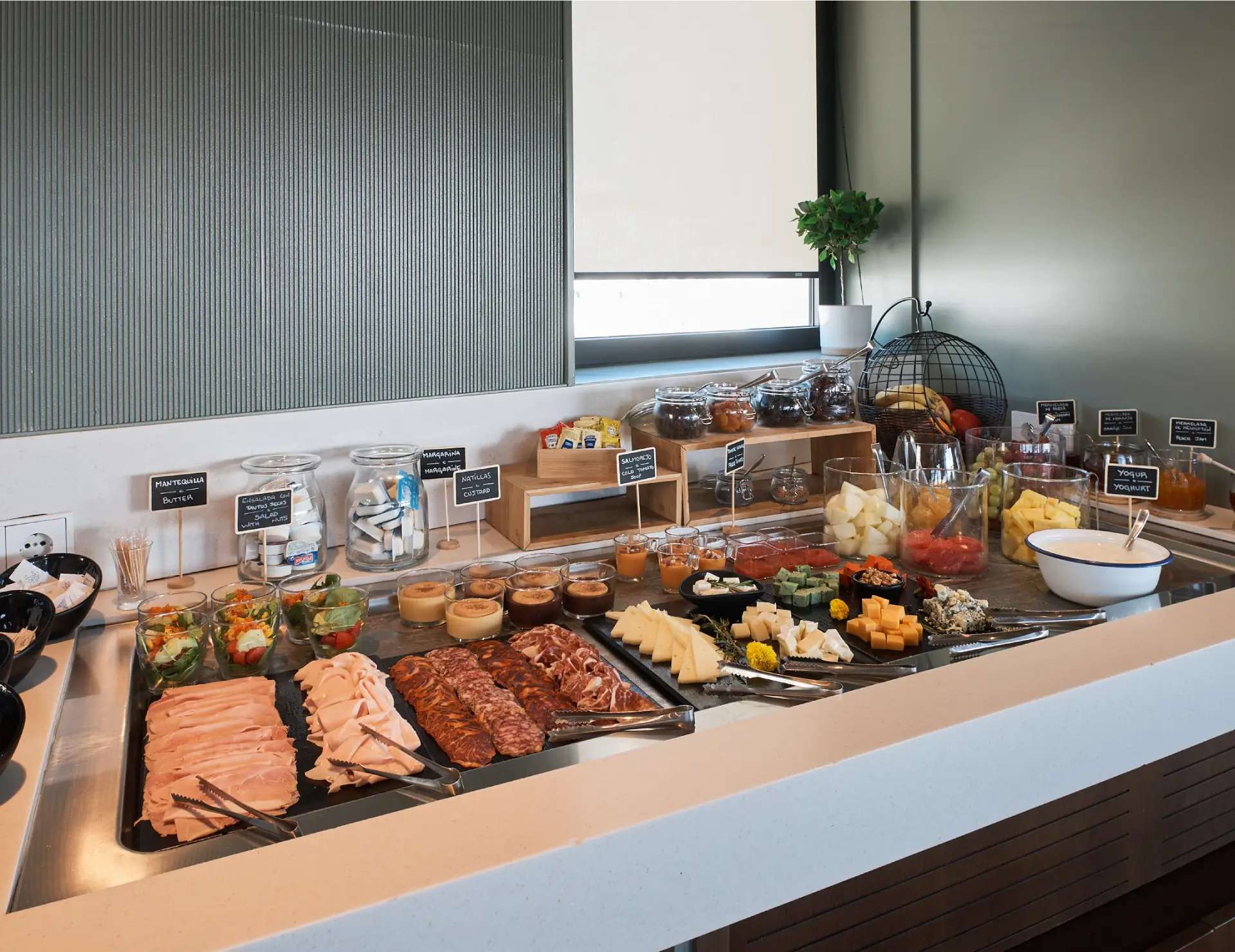 Buffet de desayuno con carnes fr&iacute;as, frutas, quesos y opciones dulces.