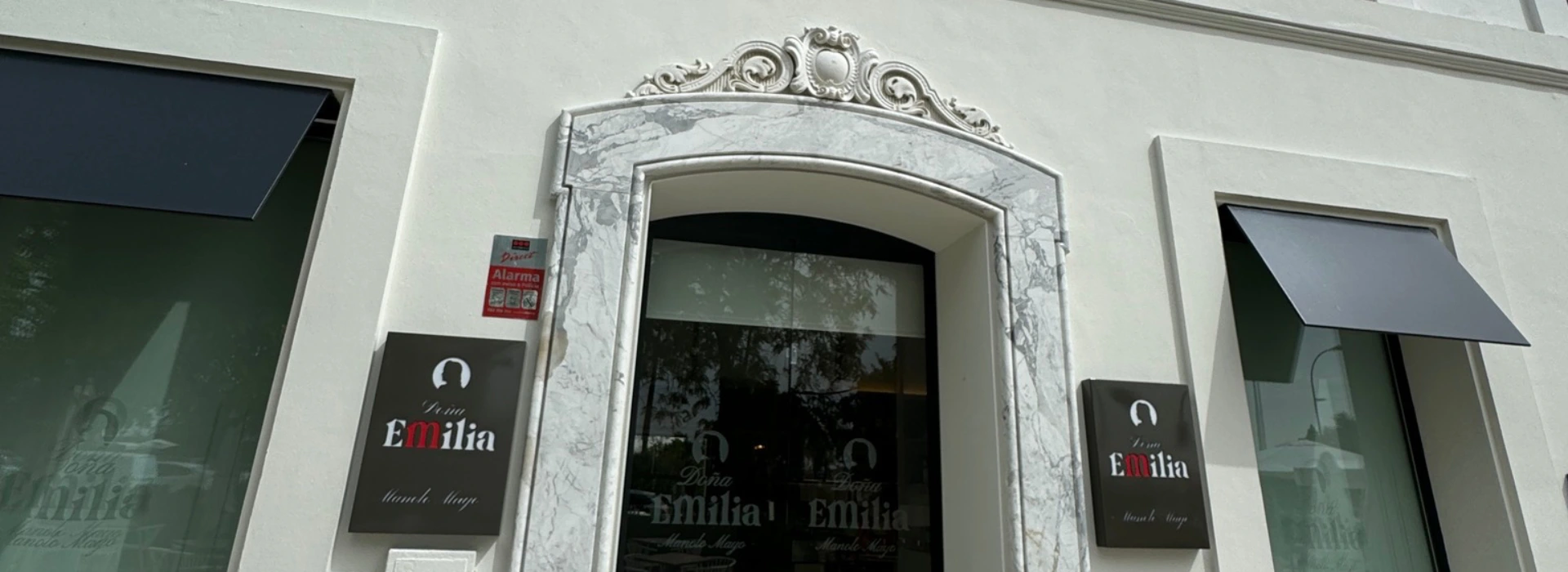 Fachada de restaurante con letreros "Do&ntilde;a Emilia" en un edificio blanco.
