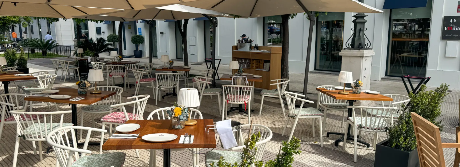 Terraza de restaurante al aire libre con mesas, sillas y sombrillas grandes.