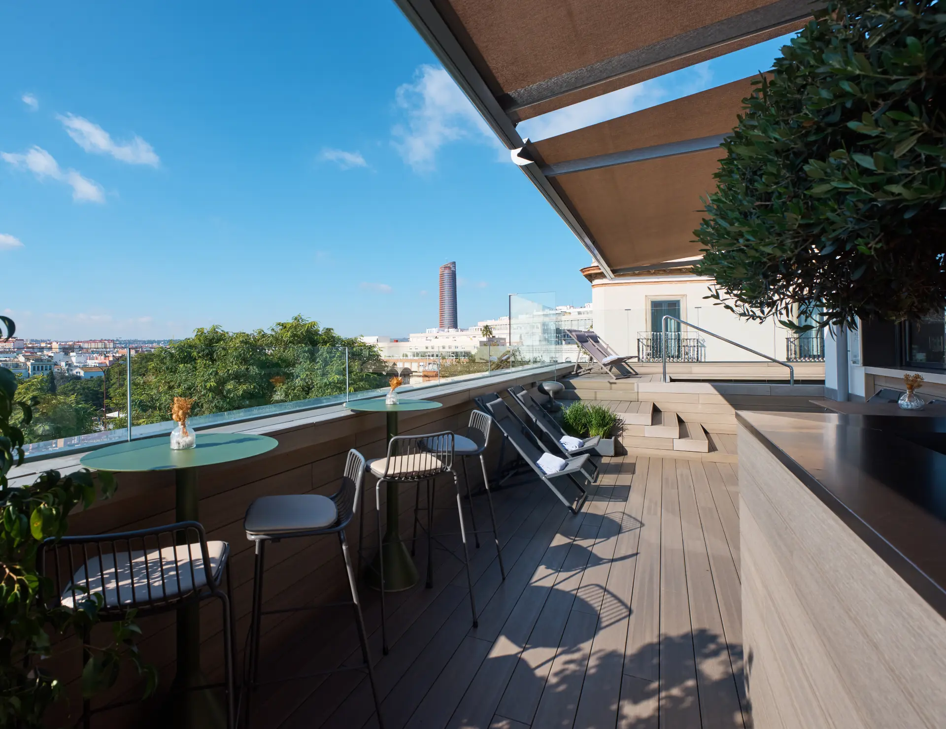 Terraza moderna con vistas a la ciudad y mesas altas bajo un cielo despejado.