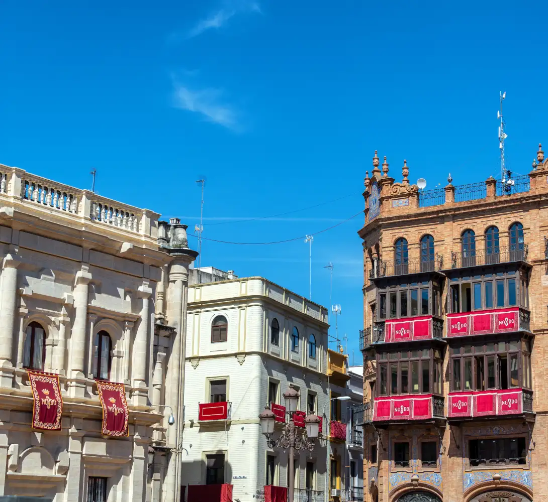 Edificios hist&oacute;ricos con decoraciones rojas bajo un cielo azul.