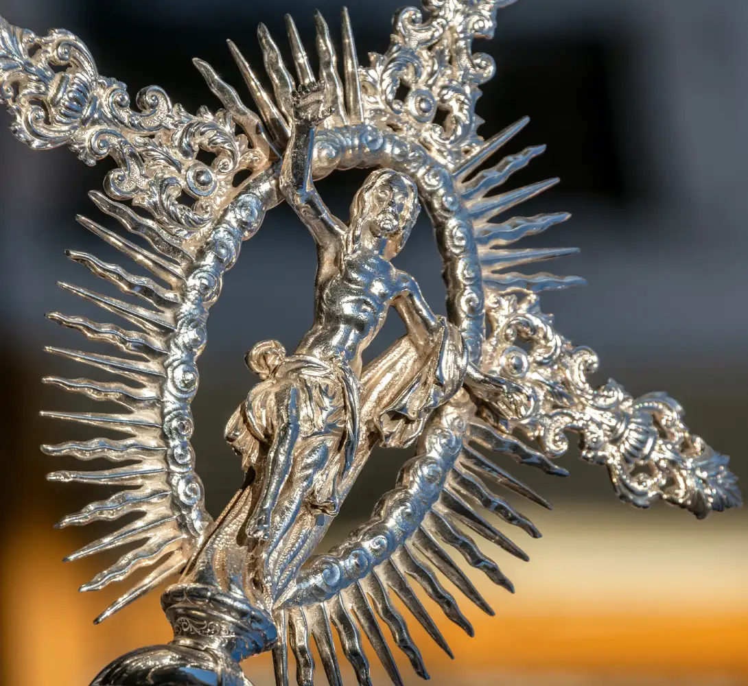 Escultura de plata detallada con figura humana y adornos florales.