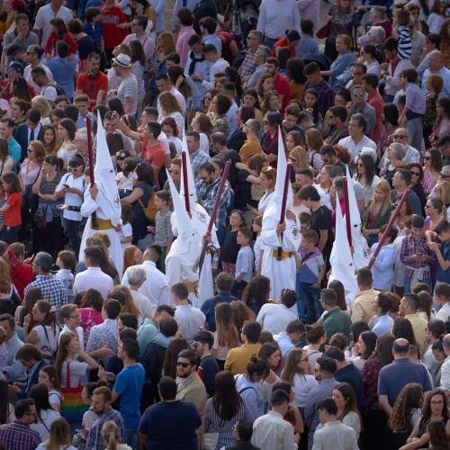 Una procesi&oacute;n religiosa con participantes entre una multitud de personas.