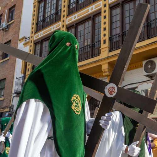 Persona encapuchada en una procesi&oacute;n, lleva una cruz negra.