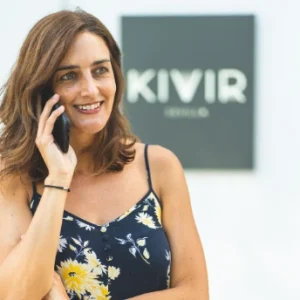 Mujer hablando por tel&eacute;fono frente a un cartel que dice "KIVIR SEVILLA".