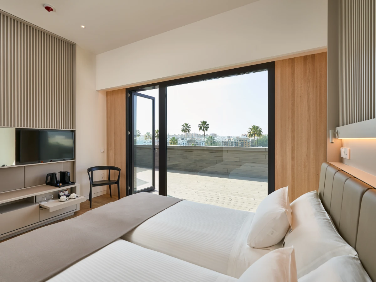 Habitaci&oacute;n moderna con terraza y vista a palmeras.