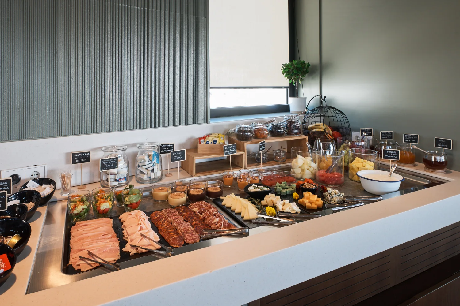 Buffet de desayuno con frutas, embutidos y variedades de quesos.