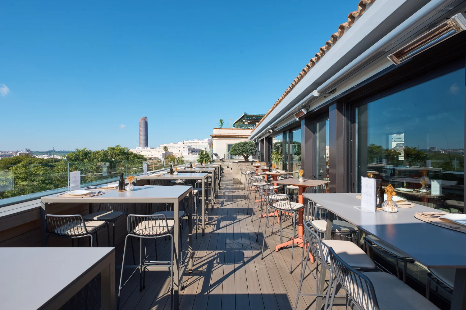 Terraza con mesas y sillas, vista urbana y cielo despejado.