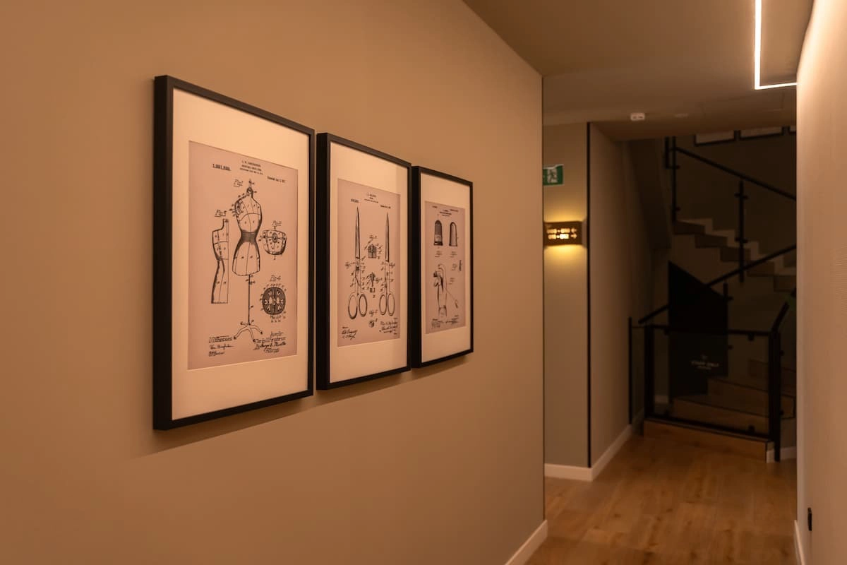 Cuadros de diseños de sastrería en un pasillo iluminado y moderno.