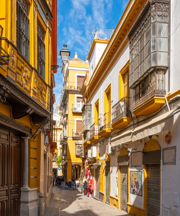 Calle estrecha con edificios amarillos y balcones en un d&iacute;a soleado.