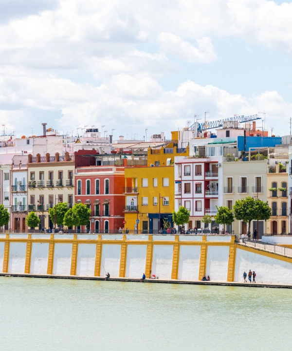 Casas coloridas junto a un r&iacute;o bajo un cielo nuboso.