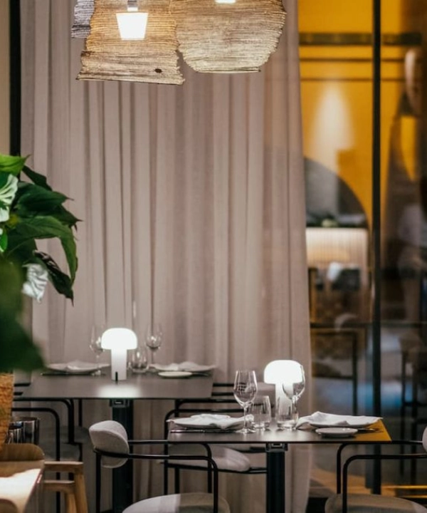 Restaurante elegante con mesas iluminadas y cortinas en el fondo.