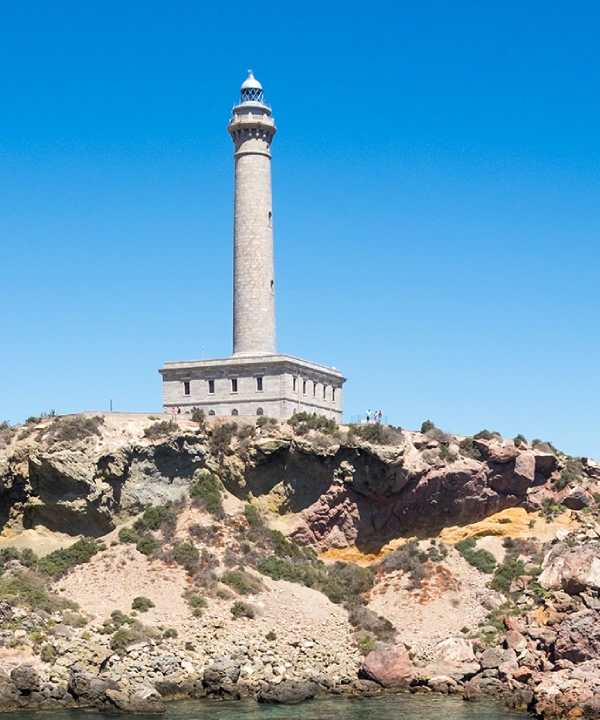 Faro sobre acantilado rocoso con cielo despejado.